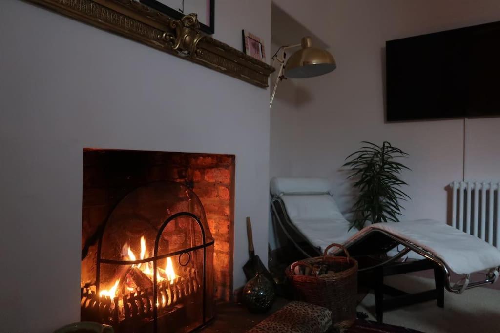 a living room with a brick fireplace with flames at Victorian Farrar Cottage in York