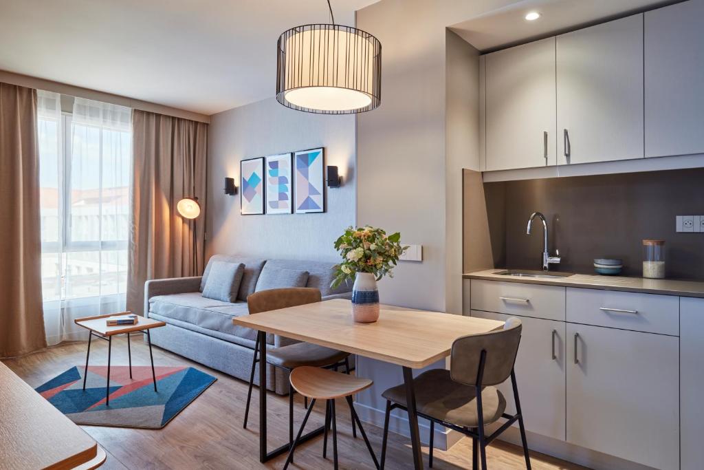Aparthotel Adagio Heidelberg في هايدلبرغ: مطبخ وغرفة معيشة مع طاولة وأريكة