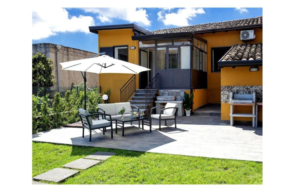 um pátio com uma mesa, cadeiras e um guarda-sol em La Sciara Etna Home em Linguaglossa