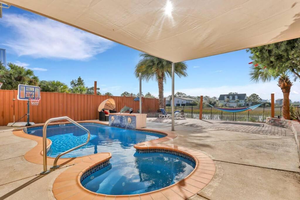 タイビーアイランドにあるLuxury 5br Home w Heated Pool Unbeatable Viewsのバスケットボール用フープ付きの裏庭のスイミングプール