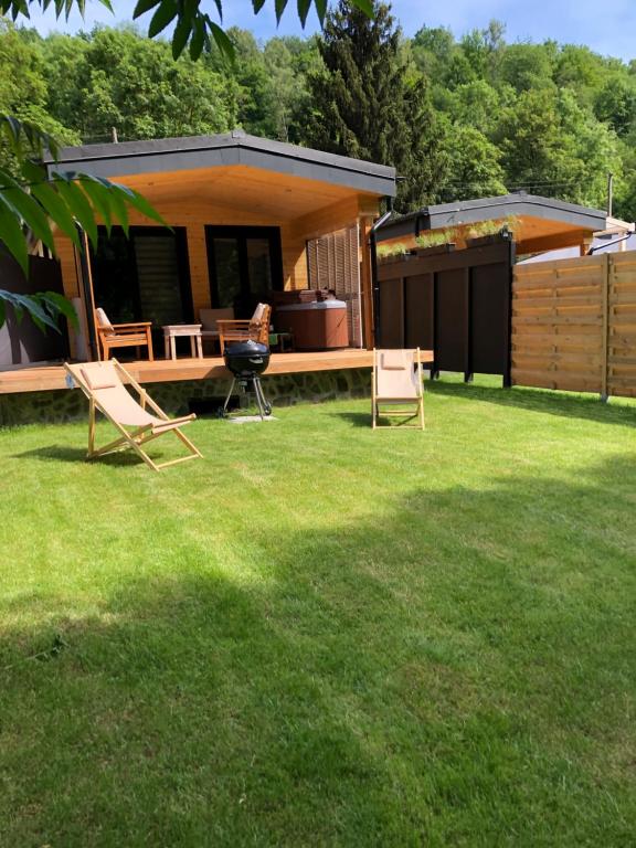 a backyard with chairs and a grill and a house at Riviera Cottage in Comblain-au-Pont