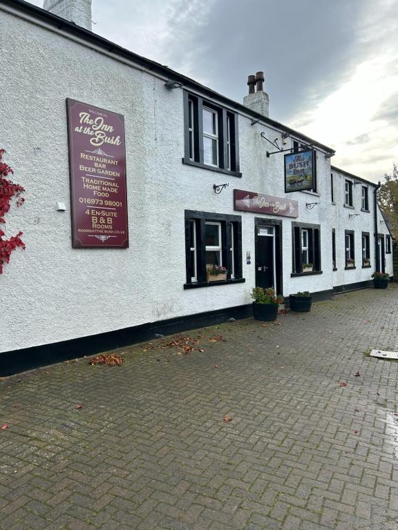 a white building with a sign on the side of it at Rooms at the Bush in Wigton