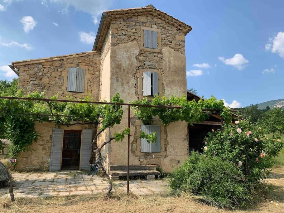 une ancienne maison en pierre avec un banc devant elle dans l'établissement Petite maison provençale, unique et calme, à Sainte-Jalle