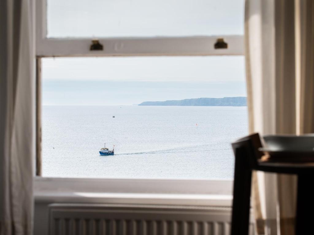a window with a view of a boat in the water at Waimea Apartments - Sea Views South Bay Scarborough Free Parking in Scarborough