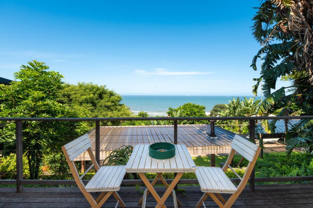 een tafel en 2 stoelen op een balkon met uitzicht op de oceaan bij The Beach Bungalow in Durban