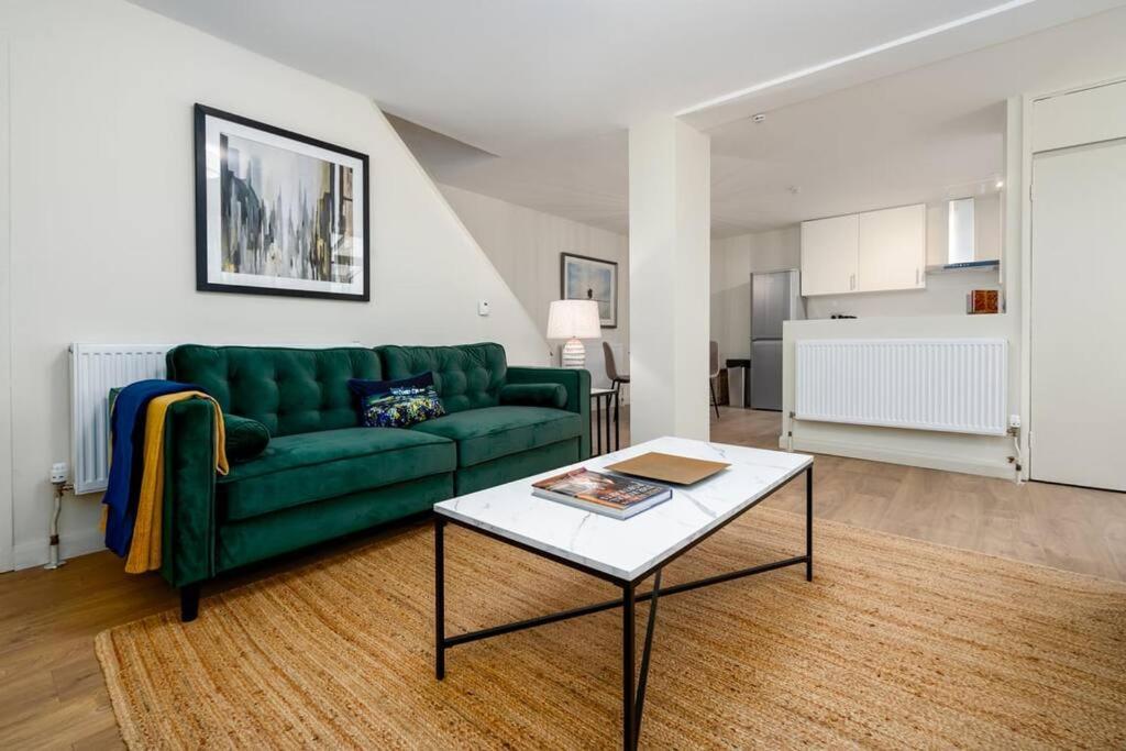 a living room with a green couch and a coffee table at GuestReady - Spacious retreat at Grange Park in London