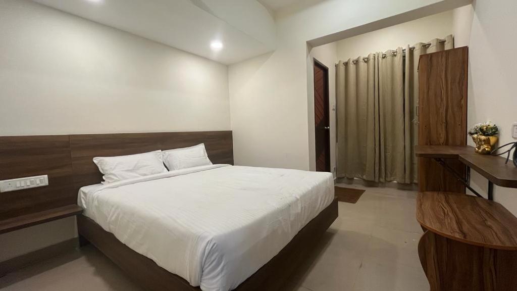 Schlafzimmer mit einem großen weißen Bett und einem Schreibtisch in der Unterkunft OGinn in Chennai