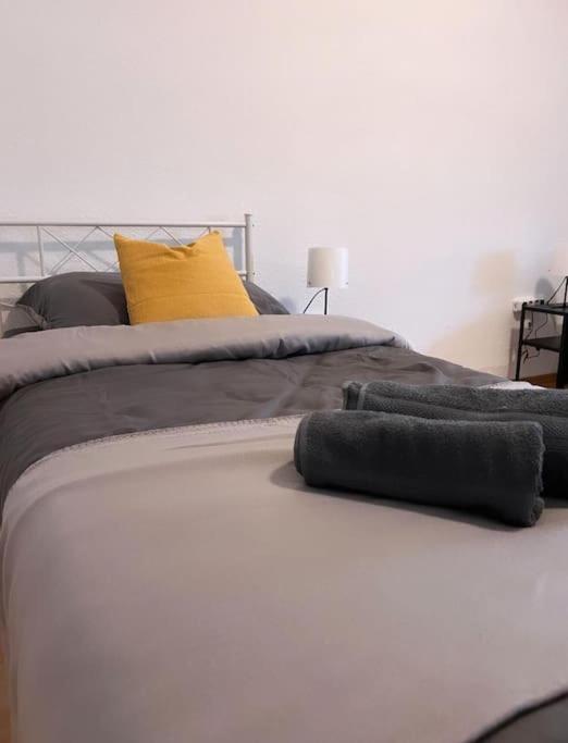 a white bed with grey and yellow pillows on it at Zentral gelegene Appartement. in Gelsenkirchen