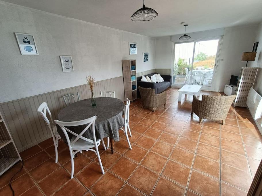 uma sala de estar com uma mesa e cadeiras e um sofá em Maison 6 pers proche plage de Tanchet em La Pironnière