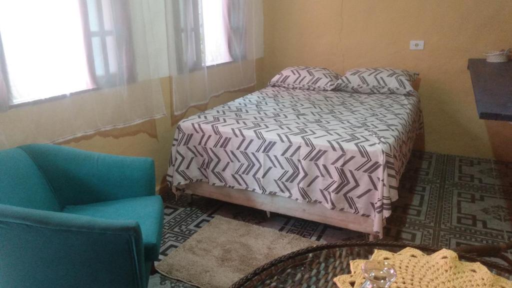 een slaapkamer met een bed, een stoel en een tafel bij Giorno Hospedaria in São Sebastião