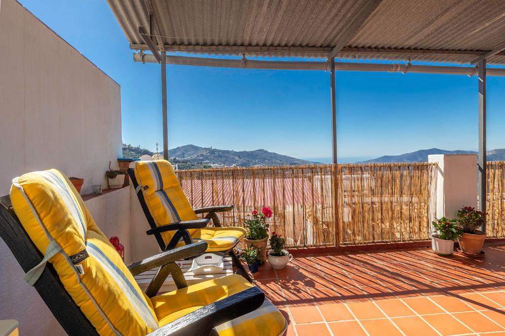two yellow chairs sitting on a balcony with a view at Casa Marlo, Spacious House in the Lively Centre of Cómpeta in Cómpeta