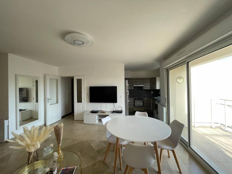 un salon avec une table et des chaises blanches dans l'établissement Duplex à proximité immédiate de l’aéroport d’Orly., à Chilly-Mazarin