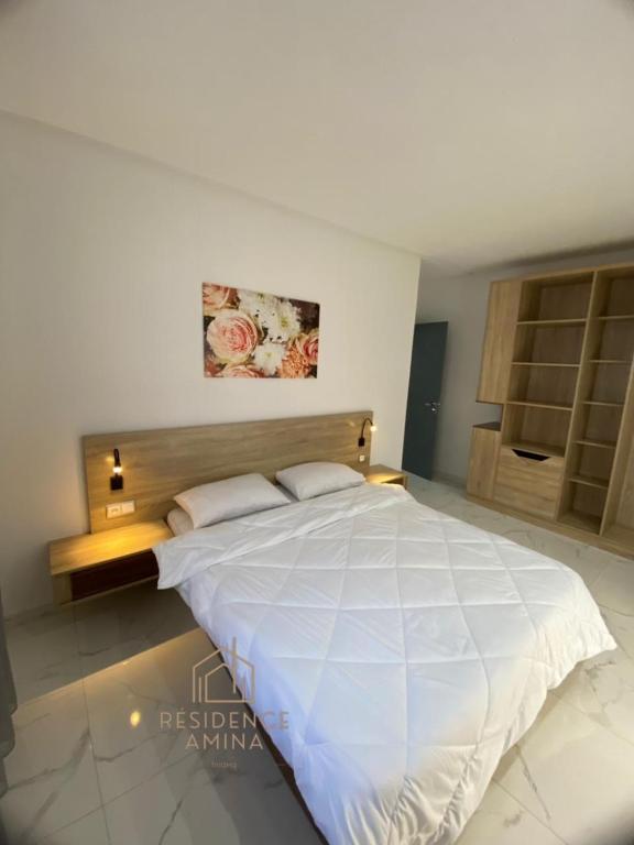 een slaapkamer met een groot wit bed in een kamer bij Résidence Amina in Fnidek