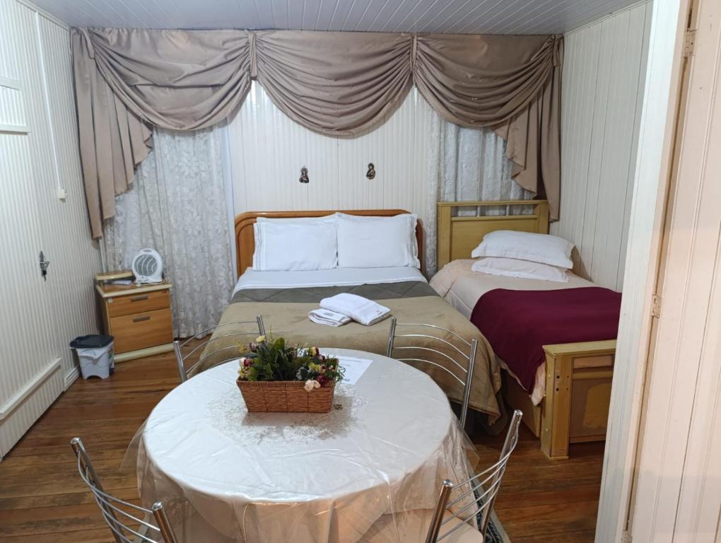 a bedroom with two beds and a table with at Pousada Vô Bira in Bom Jardim da Serra