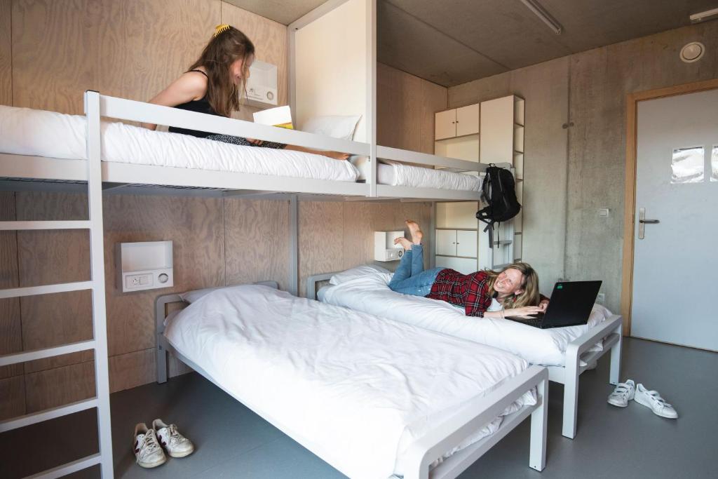 two girls laying on bunk beds in a room with a laptop at Gîte Mozaïk in Louvain-la-Neuve