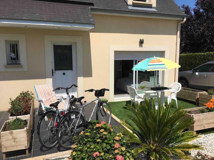 dos bicicletas estacionadas al lado de una casa con sombrilla en STUDIO TERRASSE Bayeux, en Saint-Vigor-le-Grand