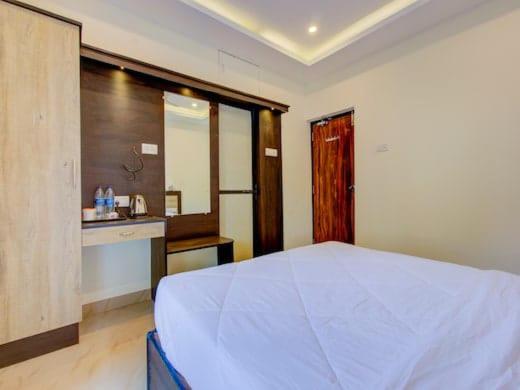 een slaapkamer met een groot wit bed en een keuken bij zoz mg2 in Oud Goa