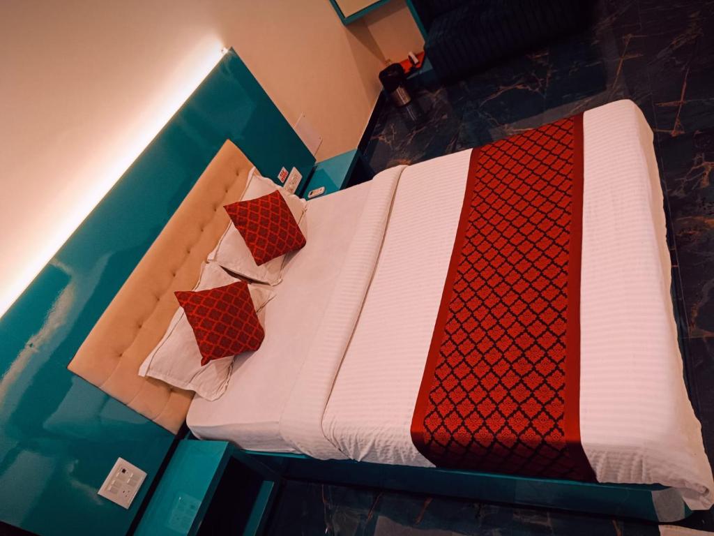Una cama con edredones rojos y blancos. en Hotel Sona Lodging & Boardging, en Mire