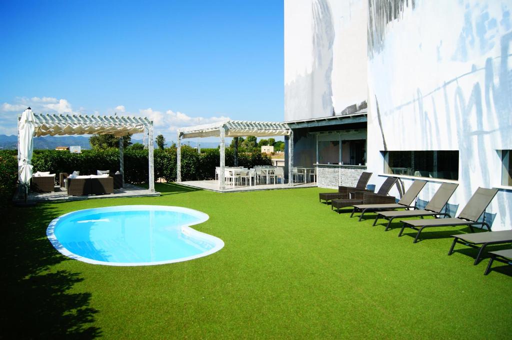 un patio con sillas y una piscina sobre césped verde en Hotel Sercotel Plana Parc en Alquerías del Niño Perdido