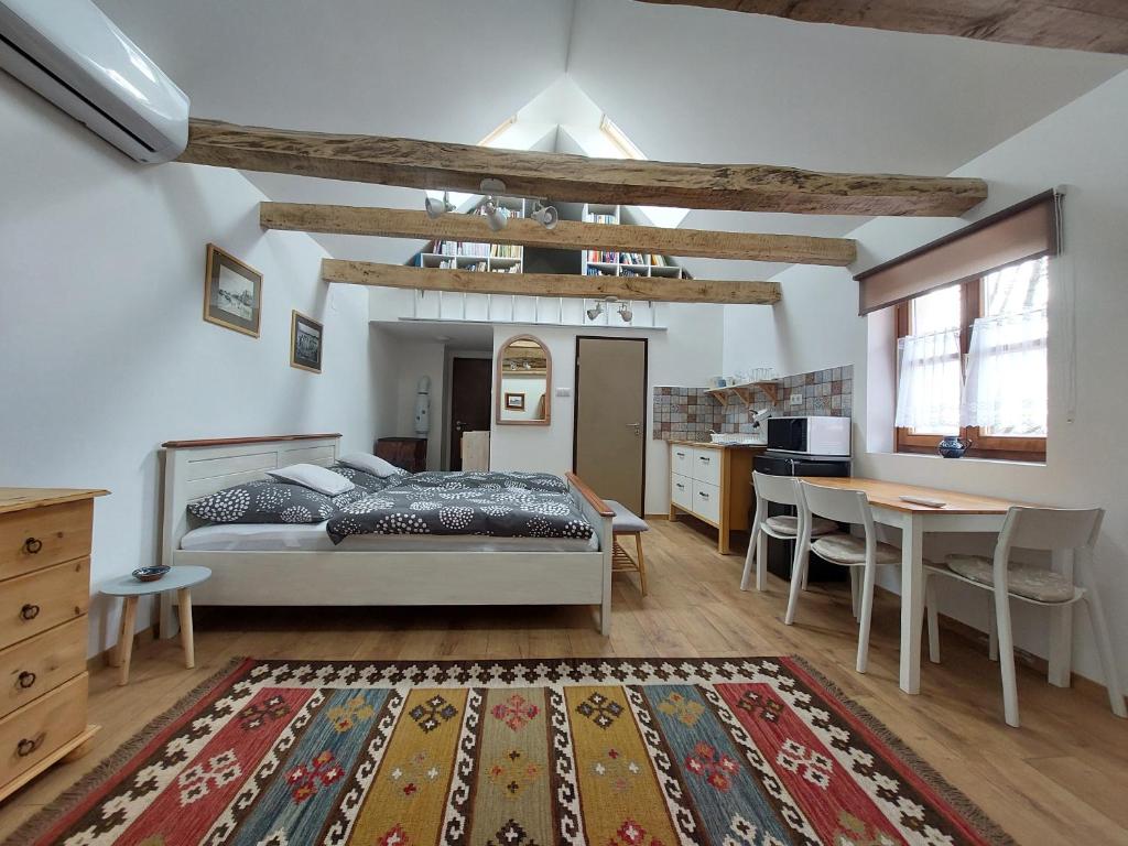 a bedroom with a bed and a table and a kitchen at Stüble Loft in Somogyhárságy