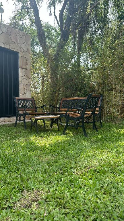 three park benches sitting in the grass near a tree at Mbokaja Paradise in San Bernardino