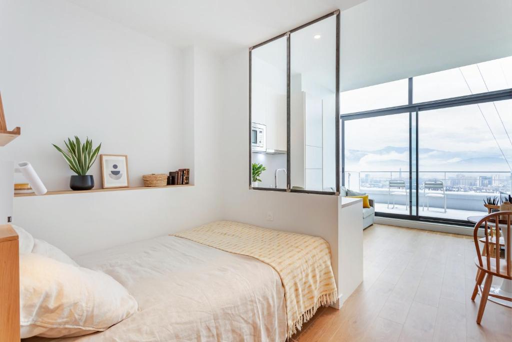 a white bedroom with a bed and a large window at Les Appartements de Grenoble in Grenoble