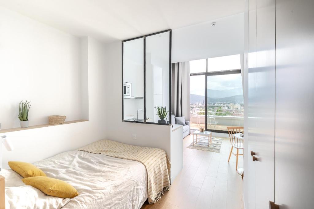 a white bedroom with a bed and a balcony at Les Appartements de Grenoble in Grenoble