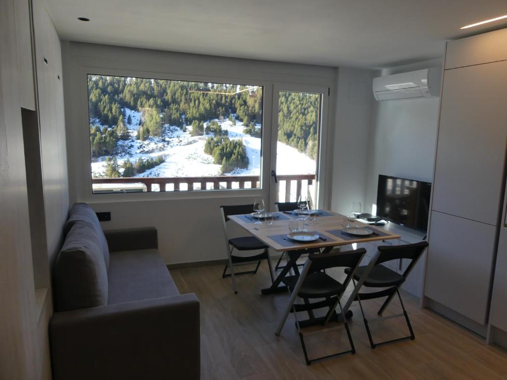 ein Esszimmer mit einem Tisch und einem großen Fenster in der Unterkunft Ideal per una escapada in Bordes d´Envalira 