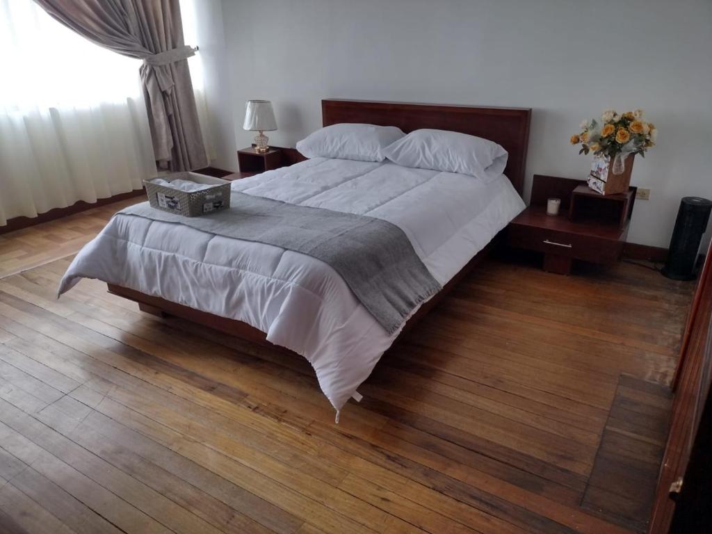 a bedroom with a large bed with a wooden floor at Acogedor Departamento Central in Loja