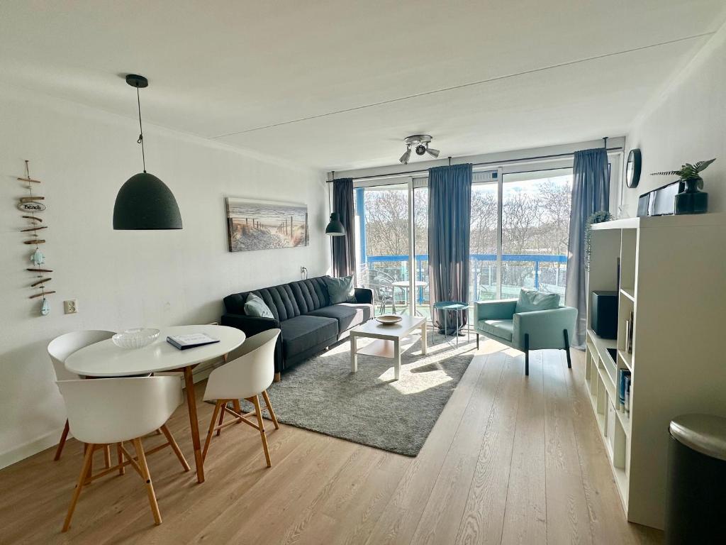 a living room with a couch and a table and chairs at Appartement Badhotel 325 in Callantsoog
