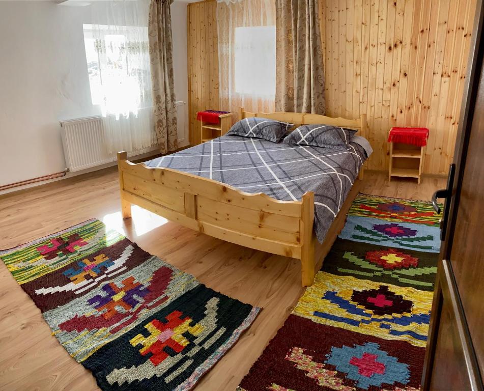 a bedroom with a wooden bed and two rugs at Cabana Elena in Gîrda de Sus