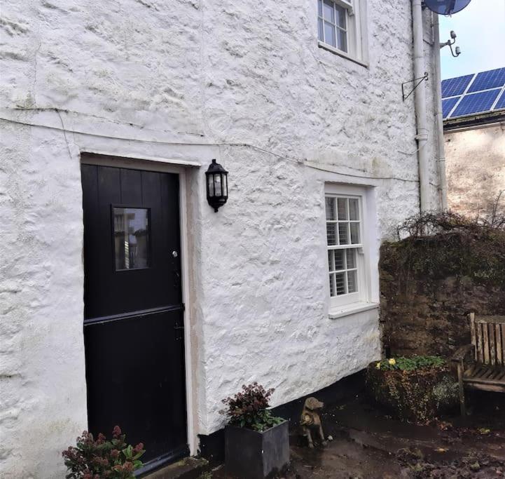 a white building with a black door and a bench at The Coach House at Lowbyer in Alston