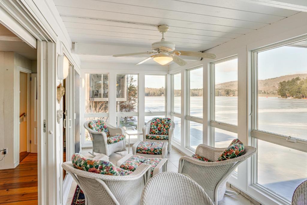 a screened in porch with chairs and a ceiling fan at Beautiful Berkshires Cottage on Lake Buel in Great Barrington