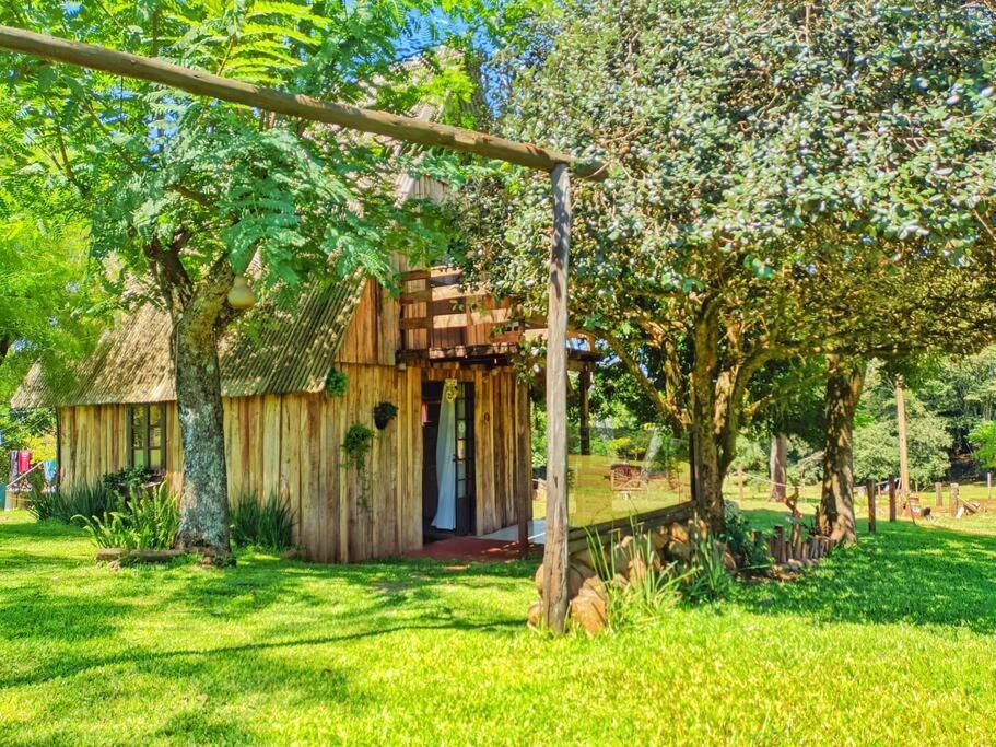 una casa con tetto di paglia in un cortile alberato di Cabana/Sítio em meio a Natureza Chalé da Collina a Sertão