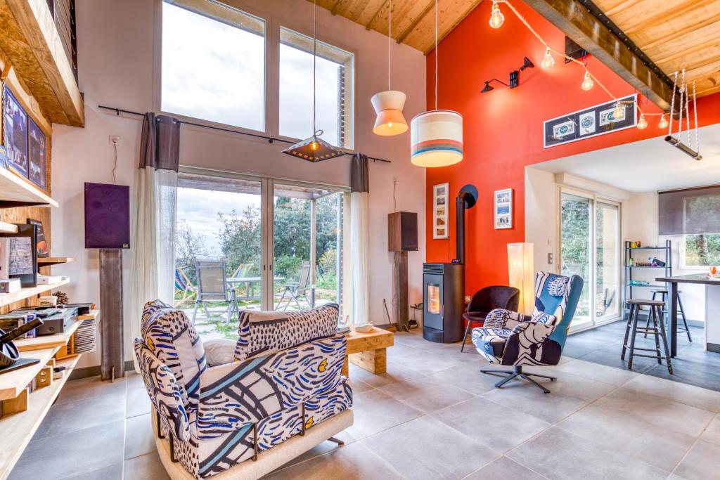 a living room with orange walls and two chairs at Maison Spacieuse avec vue dégagée in Roquessels