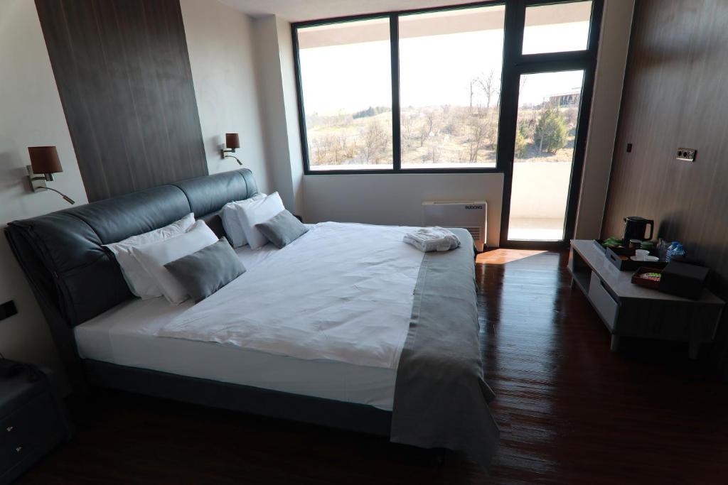 a bedroom with a large bed with a large window at Grey Star Hotel in Negotino