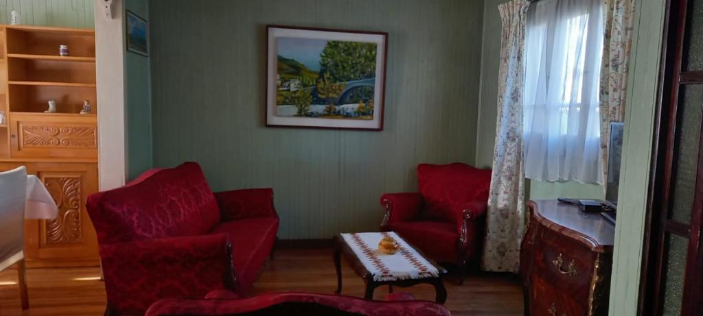 a living room with two red chairs and a table at Cabaña Los Alpes in Curacautín