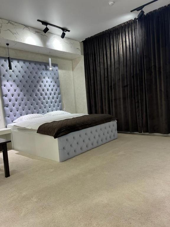 um quarto com uma cama grande e uma cortina preta em Al-Karakhan em Taraz