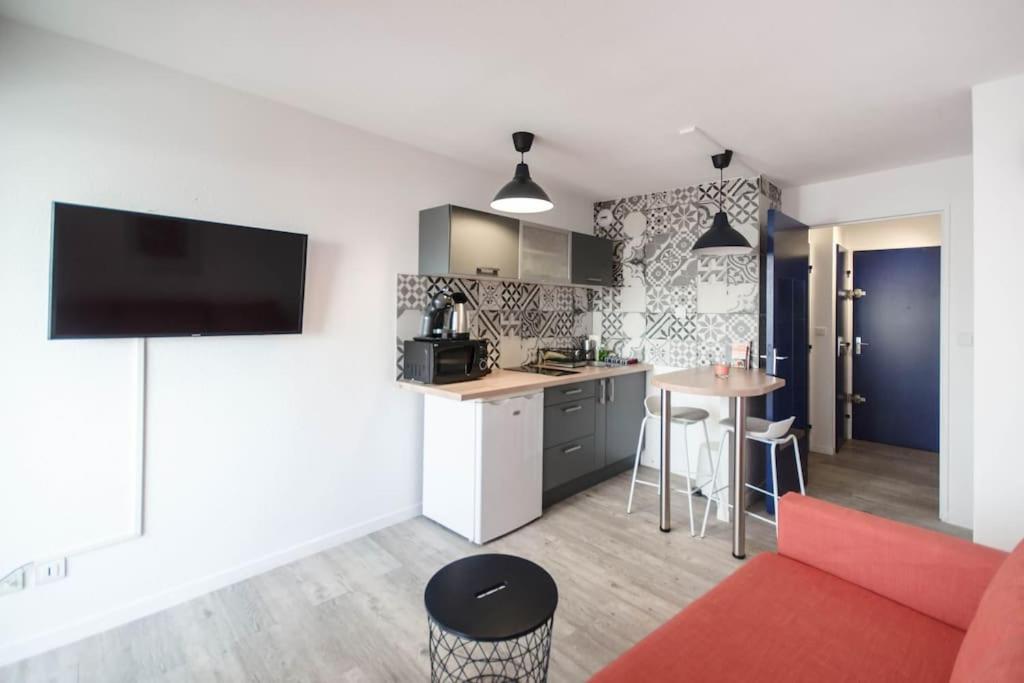 Il comprend une cuisine et un salon avec un canapé rouge. dans l'établissement Chez Anaïs - Charmant studio climatisé proche des plages, à La Grande Motte