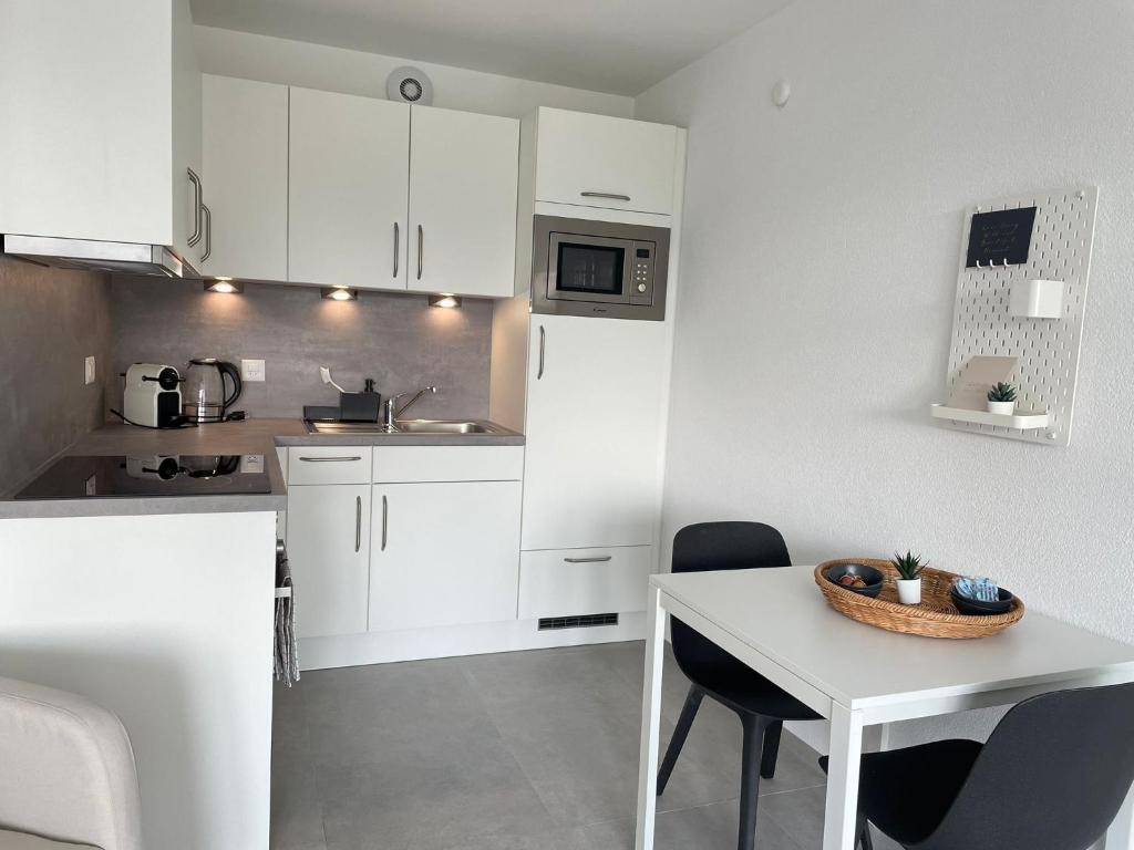 a kitchen with white cabinets and a table with chairs at H95 Studios in Basel City with Basel Card in Basel