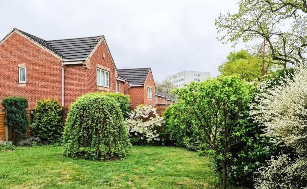 a red brick house with bushes in a yard at Spacious 6 Bedroom House Near City Centre in Birmingham