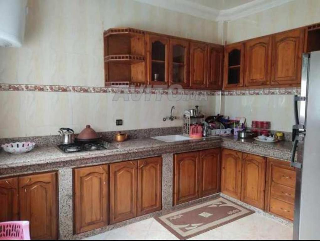 una cocina con armarios de madera y fregadero en شقتي المفروشة ب سيدي قاسم en Sidi Qacem