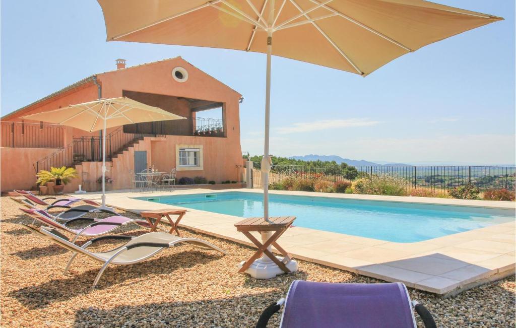 a villa with a pool and two chairs and an umbrella at Beautiful Home In Cairanne With 5 Bedrooms, Private Swimming Pool And Outdoor Swimming Pool in Cairanne