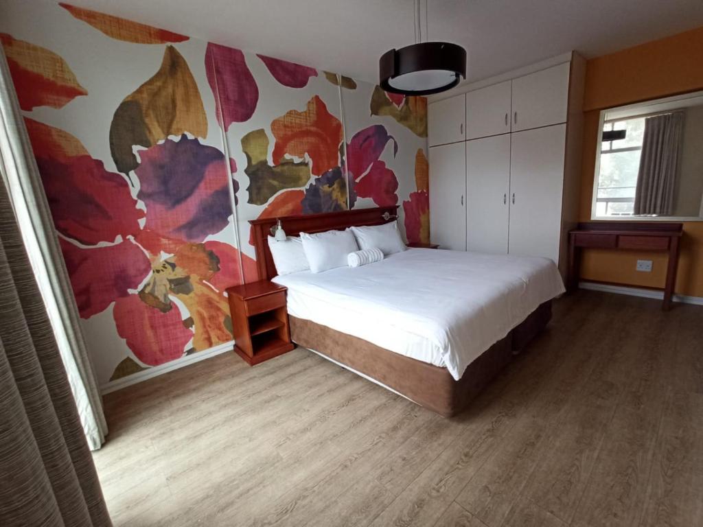 een slaapkamer met een bed en een bloemenmuur bij The Oceanic Self Catering Apartment in Durban