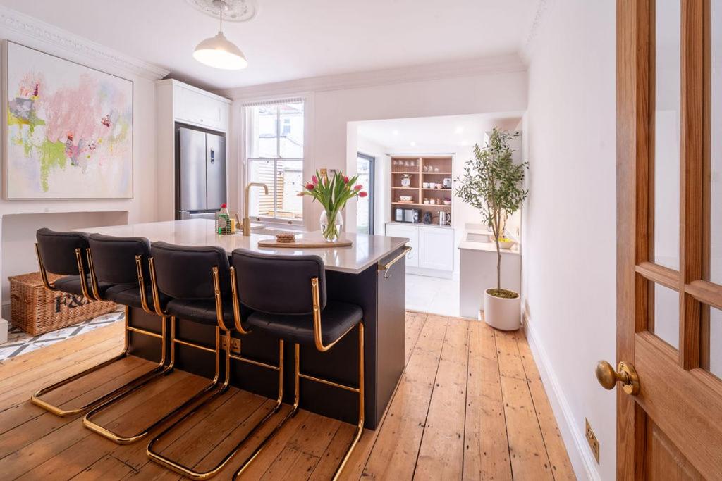 a kitchen with a black island with leather chairs at Elegant 3 bedroom home in the centre of Cheltenham in Cheltenham