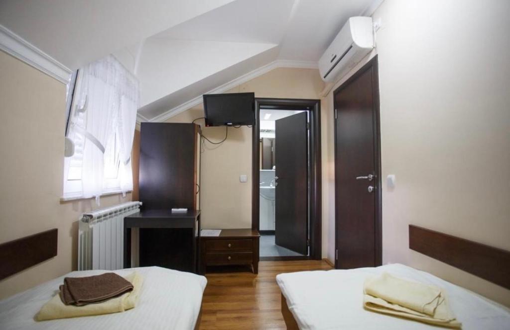 a bedroom with two beds and a door to a bathroom at STARA VAROŠ in Topola