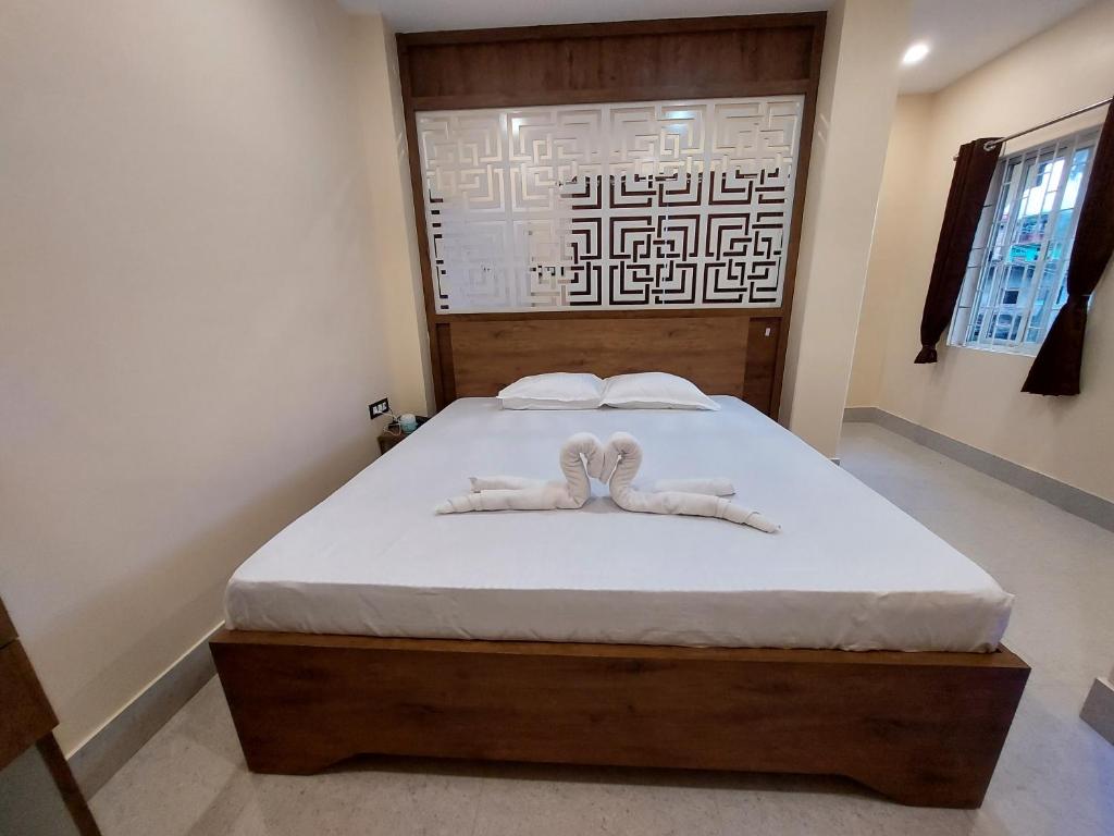 a bedroom with a bed with white sheets and two mitts at Hotel Hari Gayatri Regent in Guwahati