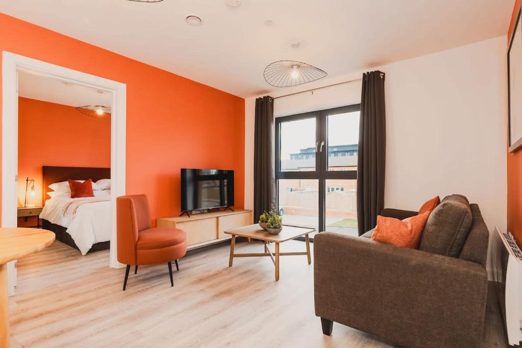 1 dormitorio con paredes de color naranja, 1 cama y 1 sofá en Modern 2 Bed Apartment, Nightingale Quarter Derby, en Derby