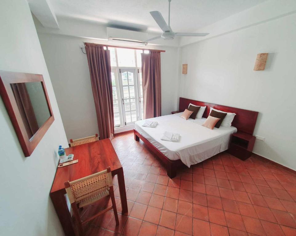 1 dormitorio con cama, mesa y ventana en Mount Bay Guest House en Mount Lavinia