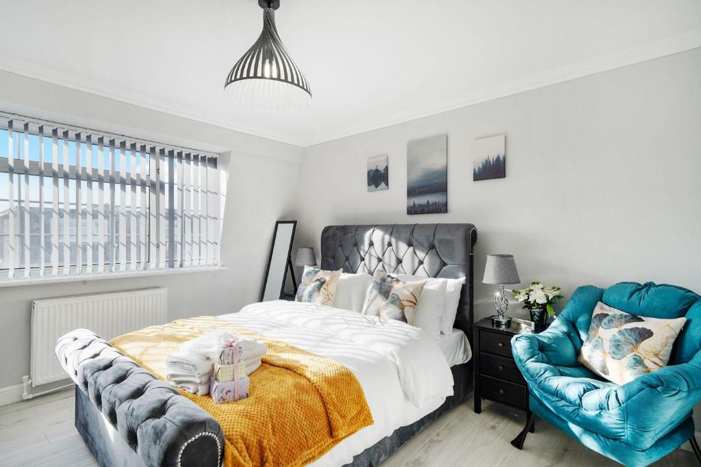 Spacious, 4 bed, Garden, Parking, ExCel London في لندن: غرفة نوم بسرير وكرسي ازرق